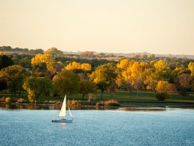 A sailboat moves across the water against the backdrop of fall foliage one evening at Branched Oak State Recreation Area.